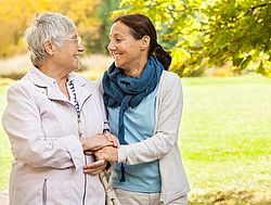 Seniorin geht mit jüngerer Frau spazieren