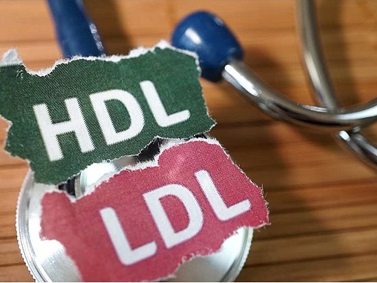 Symbolische Darstellung von HDL- und LDL-Cholesterin mit Schildern und Stethoskop